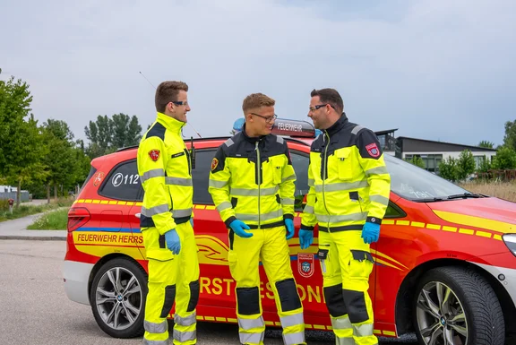 Drei Feuerwehrdienstleistende in Einsatzkleidung vor dem First Responder Fahrzeug